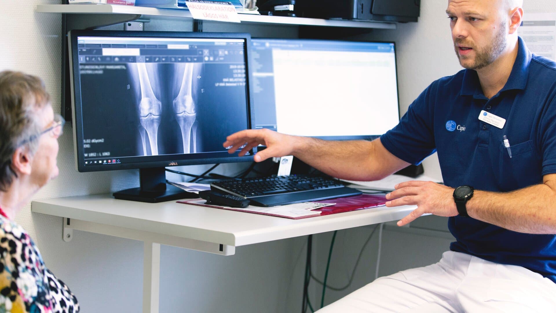 Sjukvårdpersonal visar patient röntgenbilder på en skärm