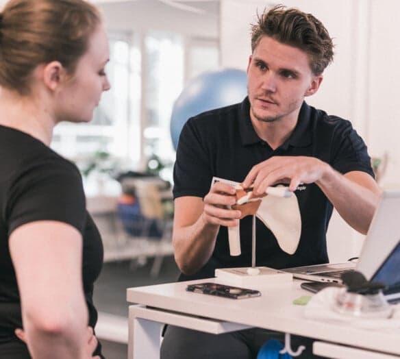 fysioterapeut visar patient en axelmodell