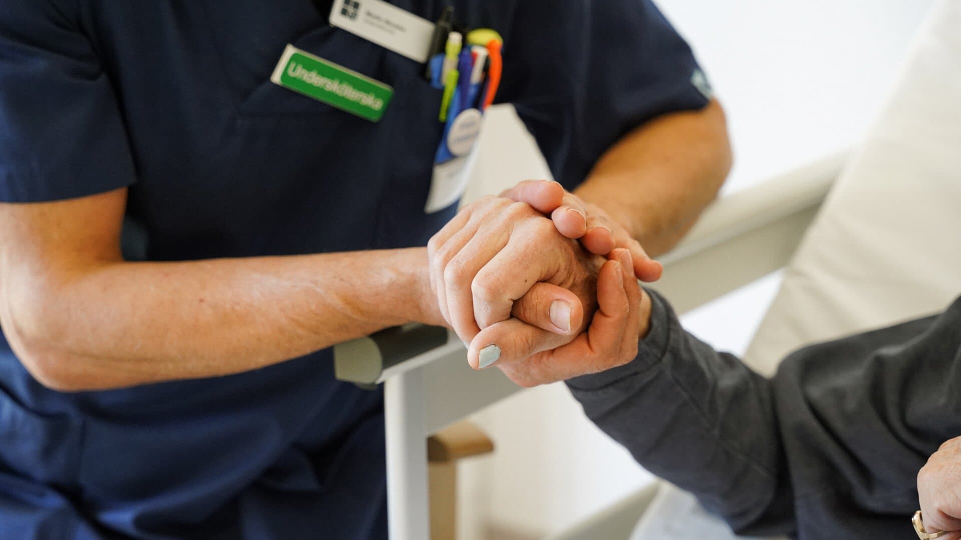 Undersköterska som håller en äldre person i handen