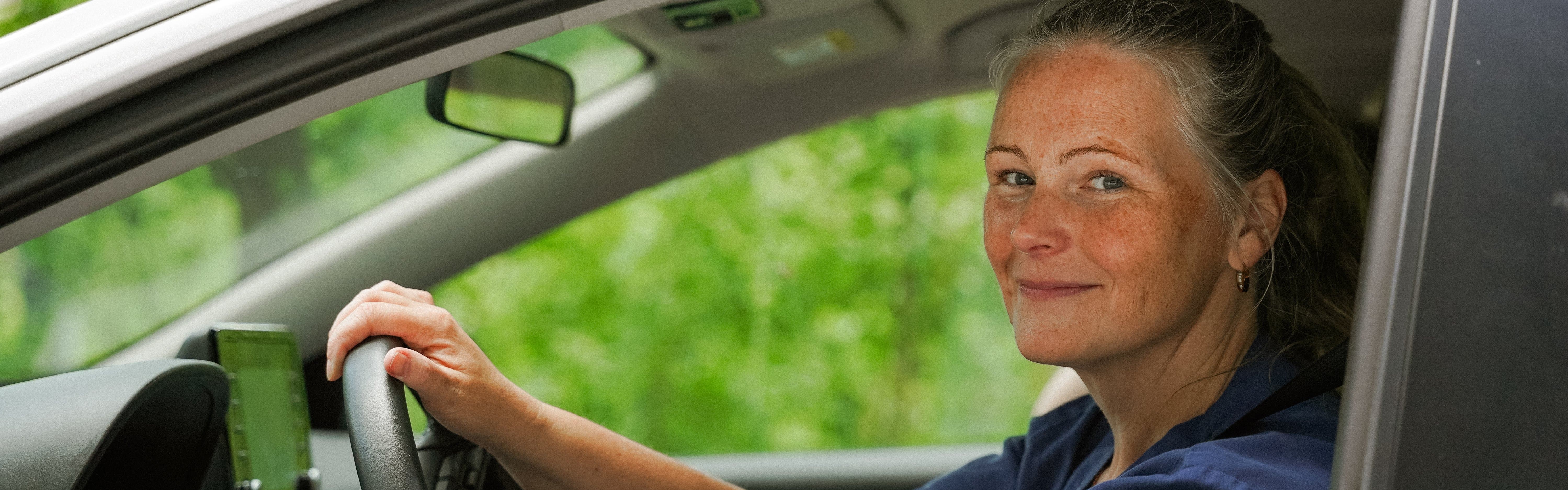 Närbild på en sjuksköterska som sitter i bil och tittar ut genom bilrutan