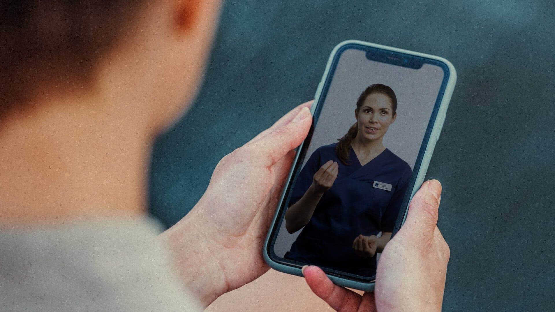 Kvinna håller i en mobil och visar Capios app Kvinna håller i en mobil och visar Capios app