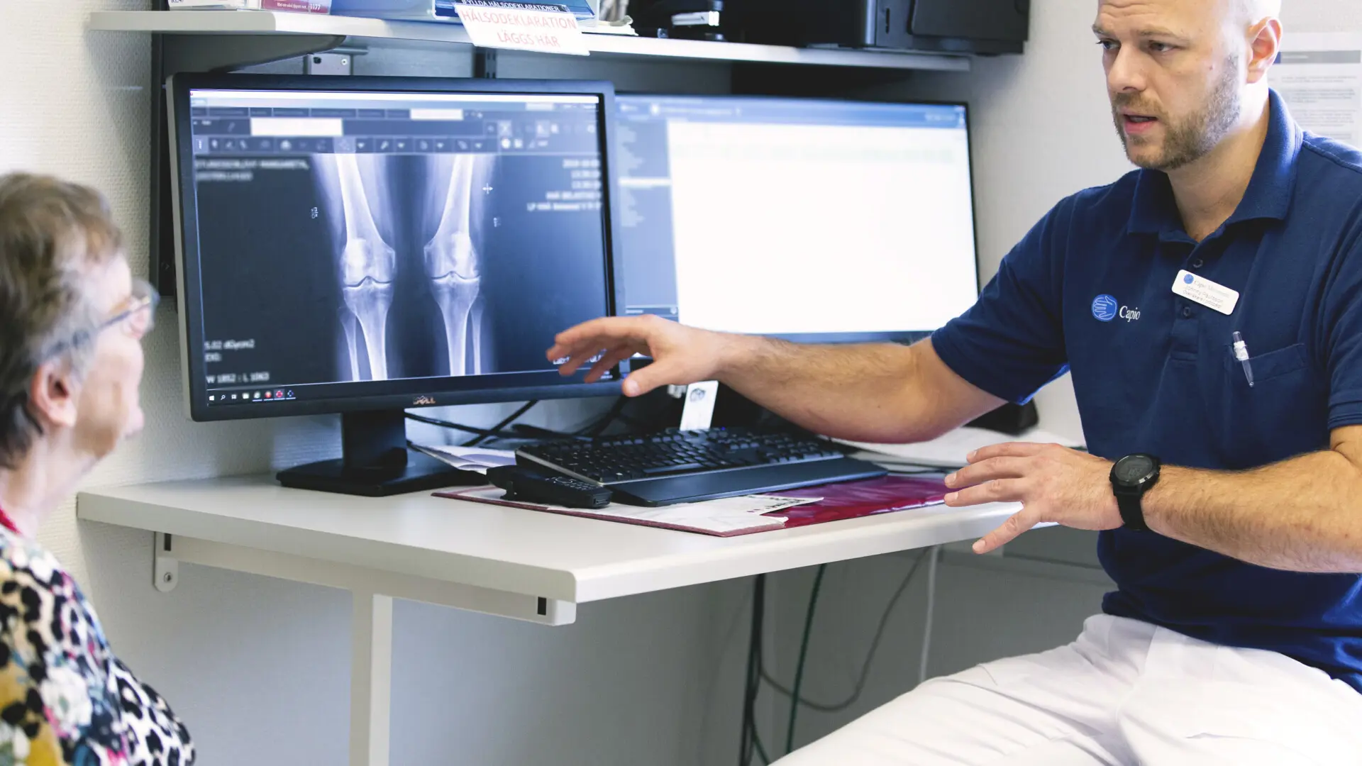 Sjukvårdpersonal visar patient röntgenbilder på en skärm